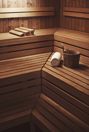 A wooden sauna bench with a towel and a wooden bucket. - Hotel Waldhuus Davos (Davos)