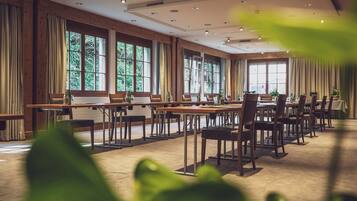 Une salle de conférence dotée de plusieurs tables et chaises, de grandes fenêtres et d’un éclairage au plafond.