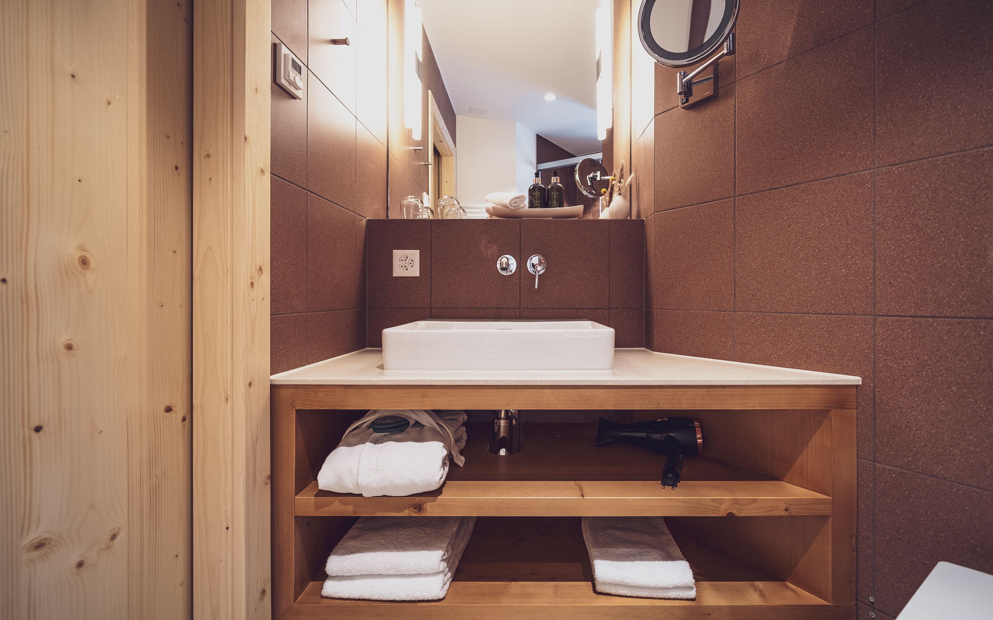 A modern bathroom with a wooden vanity, a white sink, and a mirror.