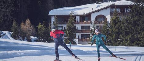 Two skiers on a snowy slope with a building in the background.