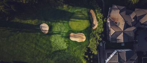 Ilmakuva asuinalueesta, jossa on golfkenttä, taloja ja tie.