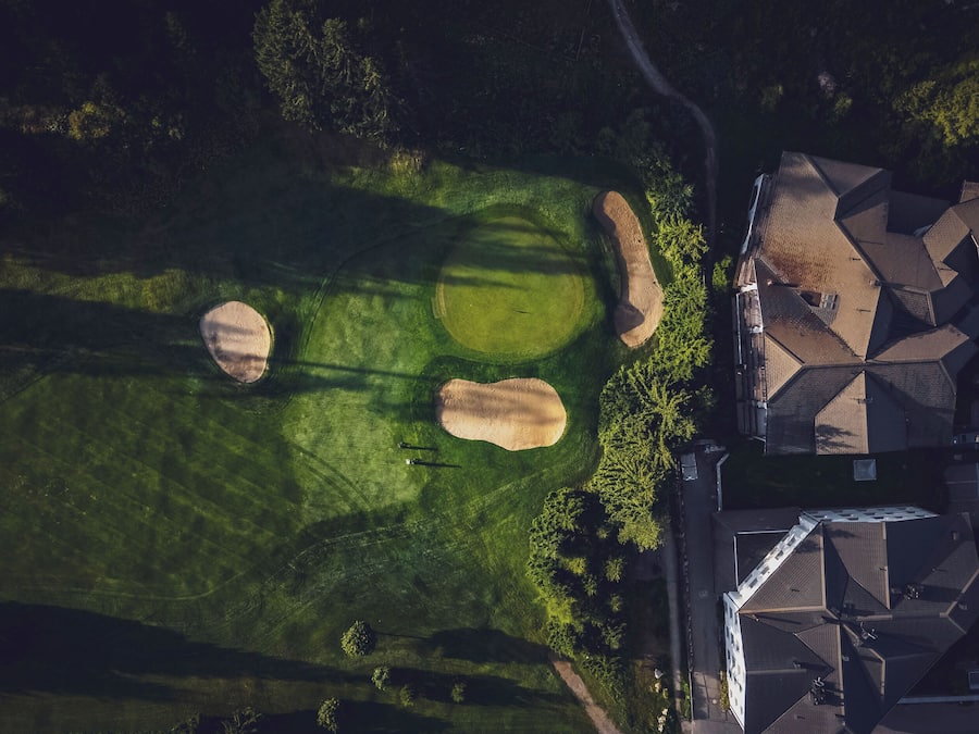 An aerial view of a residential area with a golf course, houses, and a road.