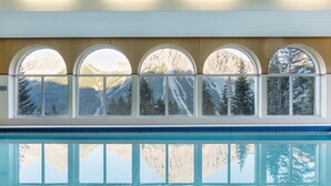 A swimming pool with a view of mountains through arched windows. - Sunstar Hotel Arosa (Arosa)