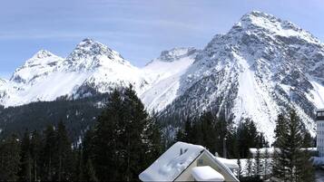 Une station de montagne avec des sommets enneigés, un chalet à étages et un parking.