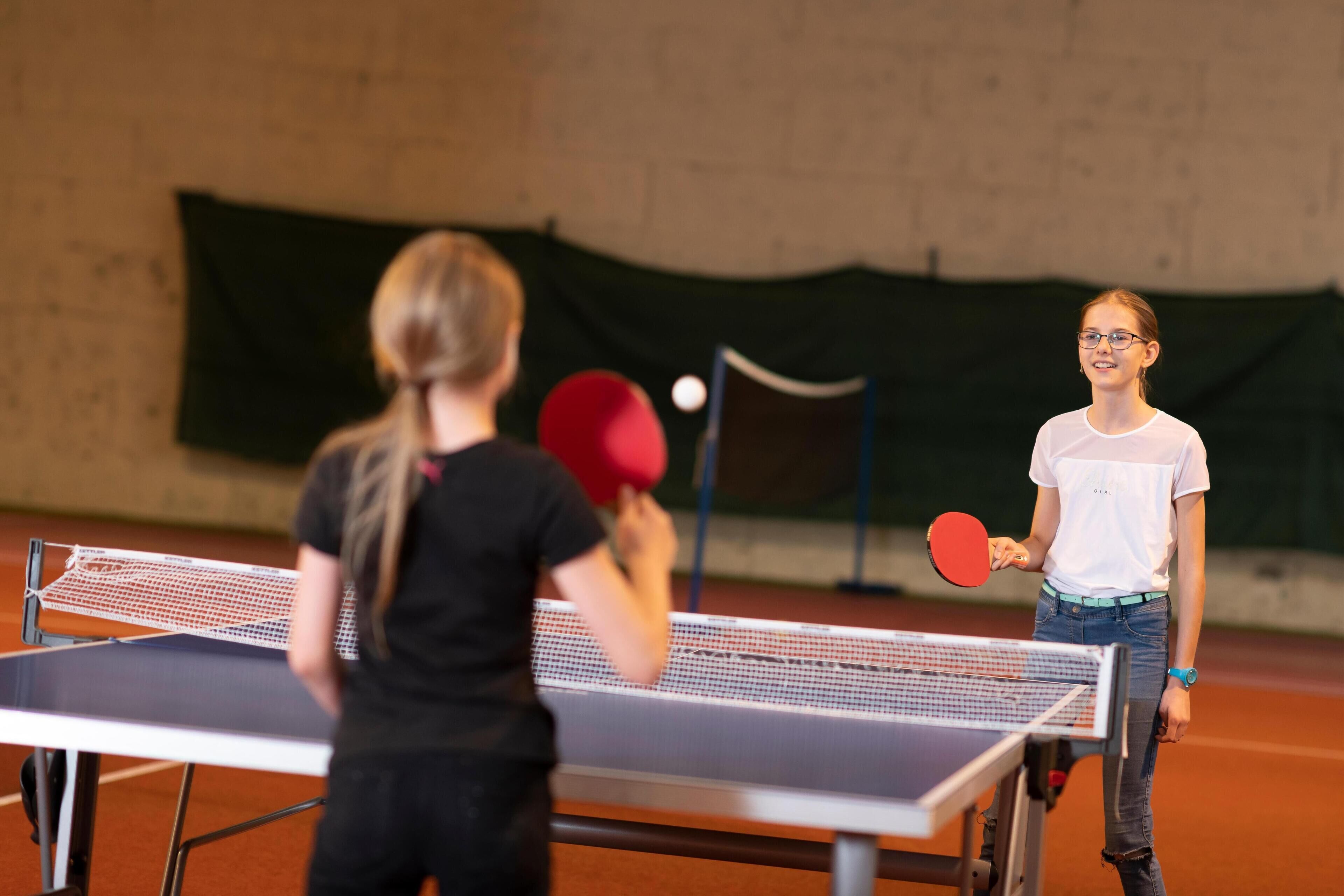 A table tennis table in an indoor setting with a net in the middle.