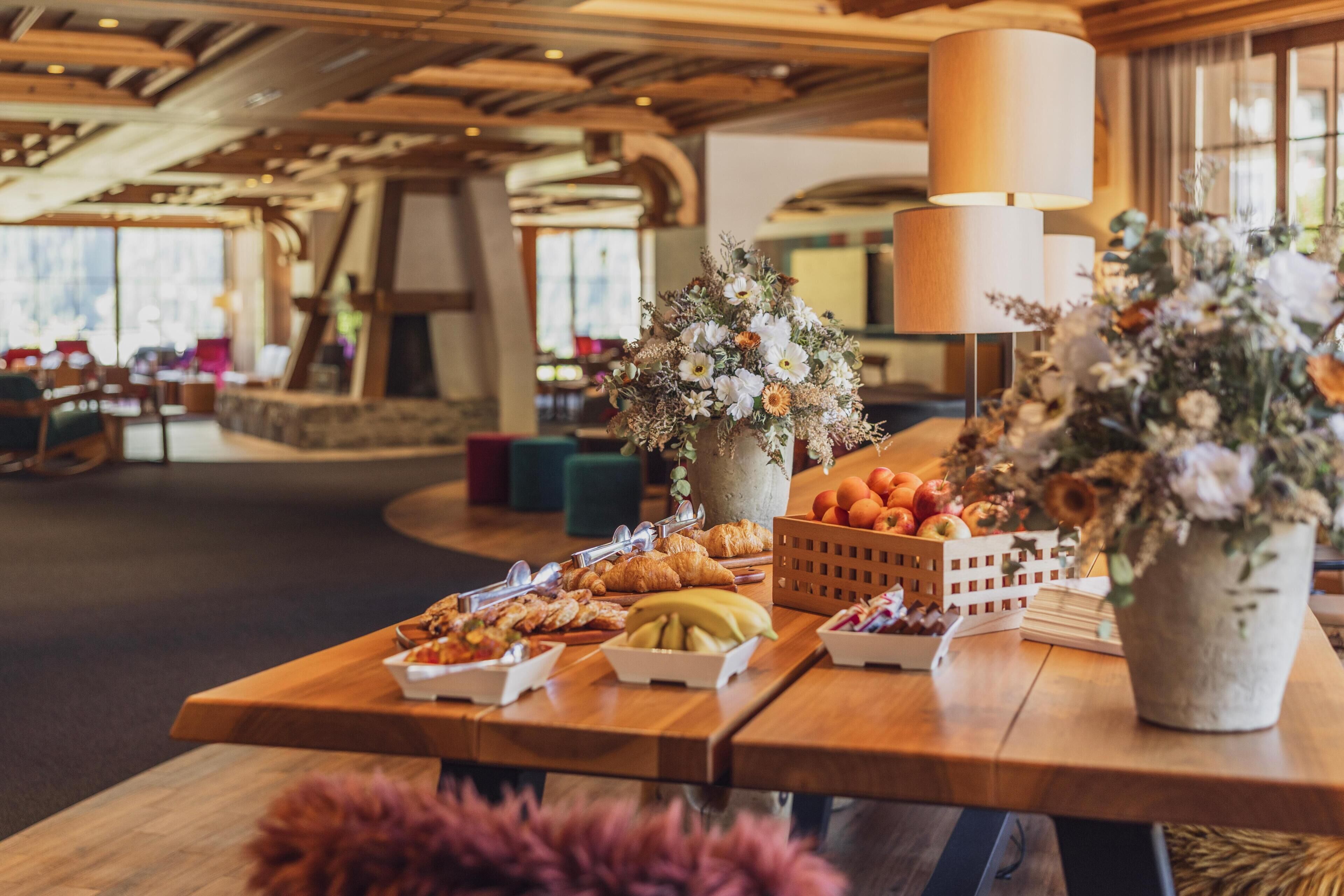 Un buffet de petit-déjeuner proposant une variété de plats et agrémenté de compositions florales, le tout dans un cadre chaleureux au décor intérieur en bois.