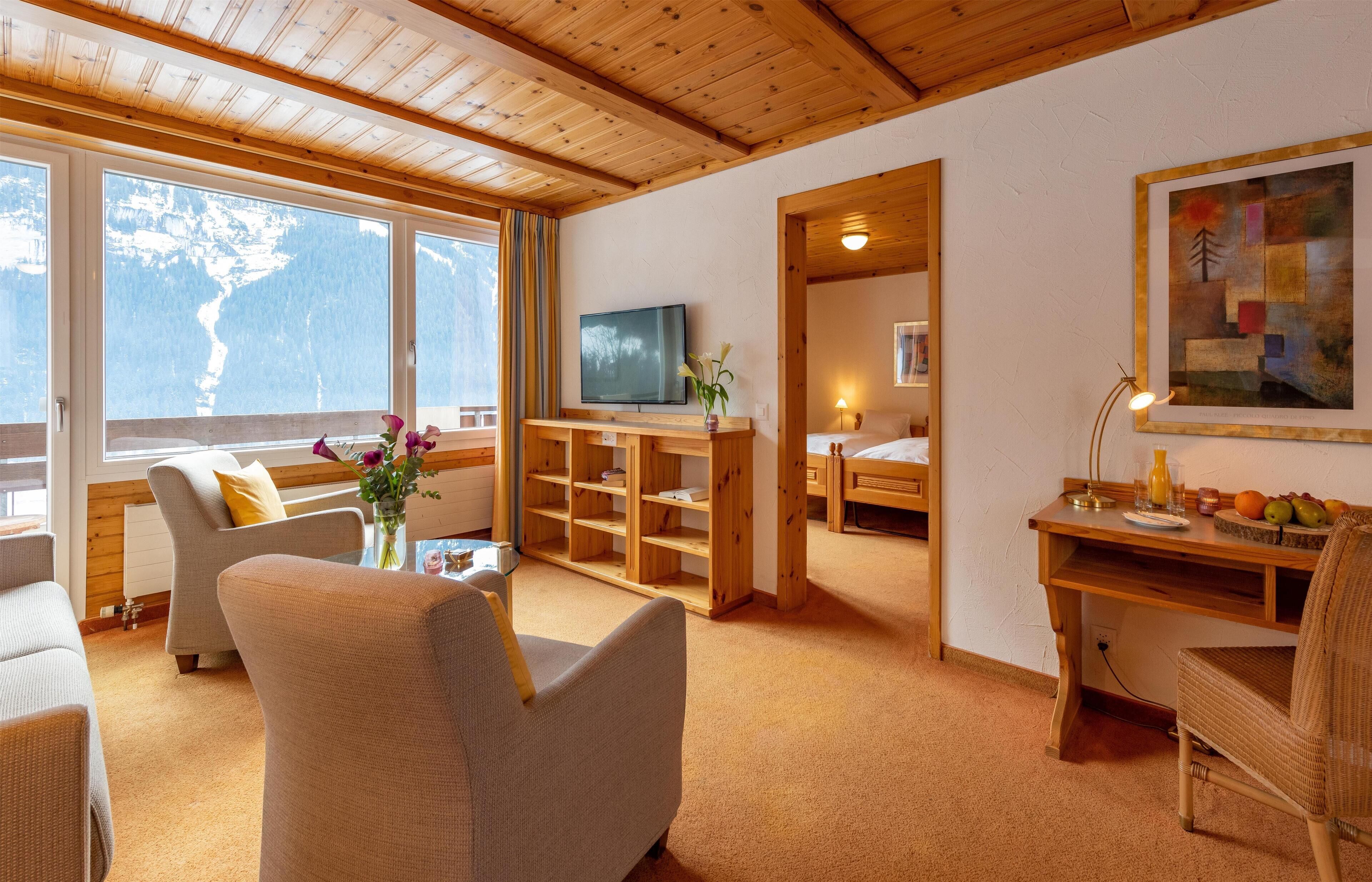 Une pièce confortable avec un plafond en bois, une télévision, un bureau avec une lampe et un lit.