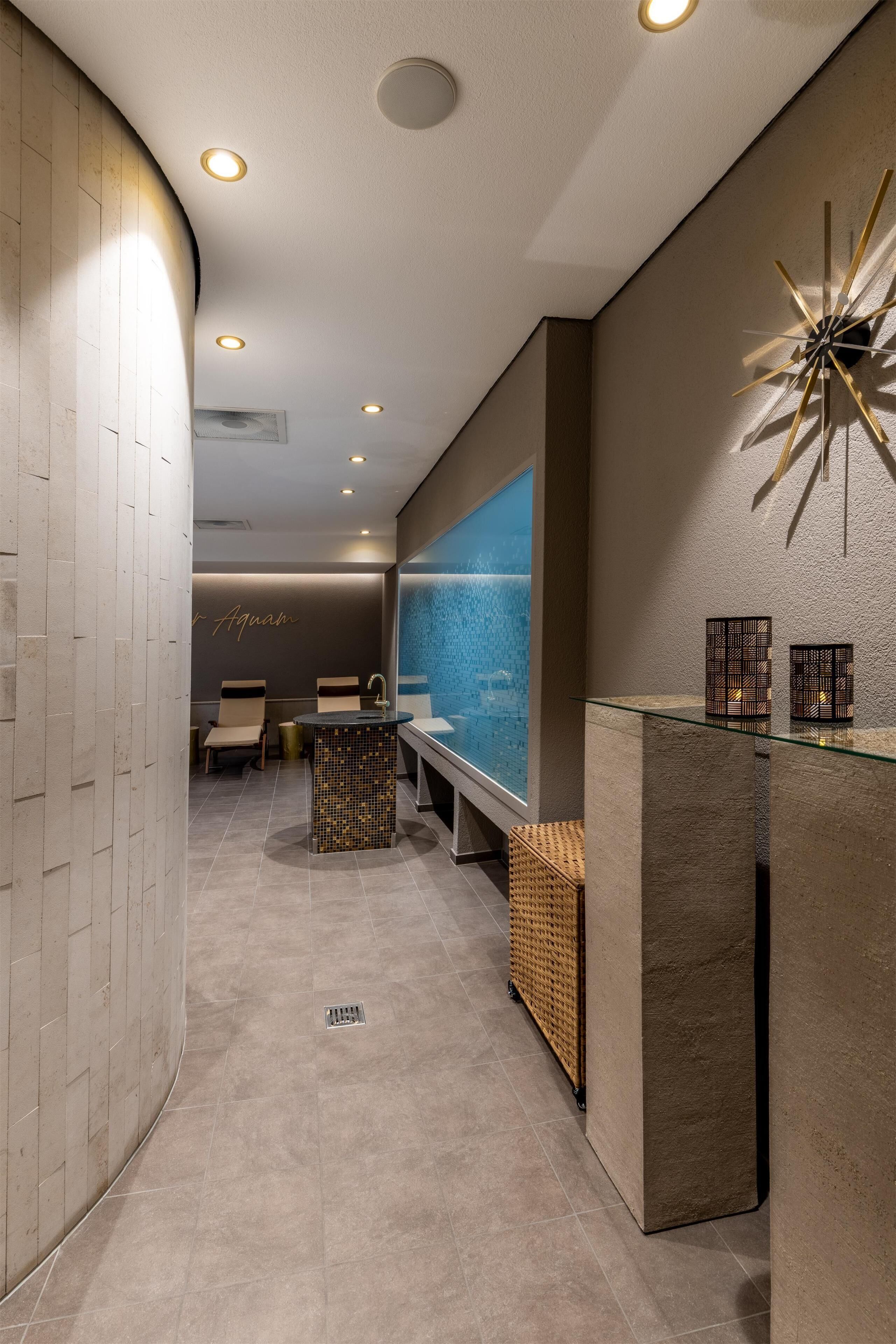 A modern spa area with a reception desk, seating, and a large water feature.