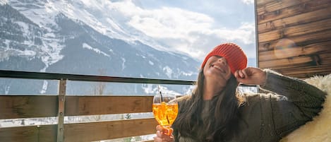 A person sitting on a wooden bench with a mountain view in the background.