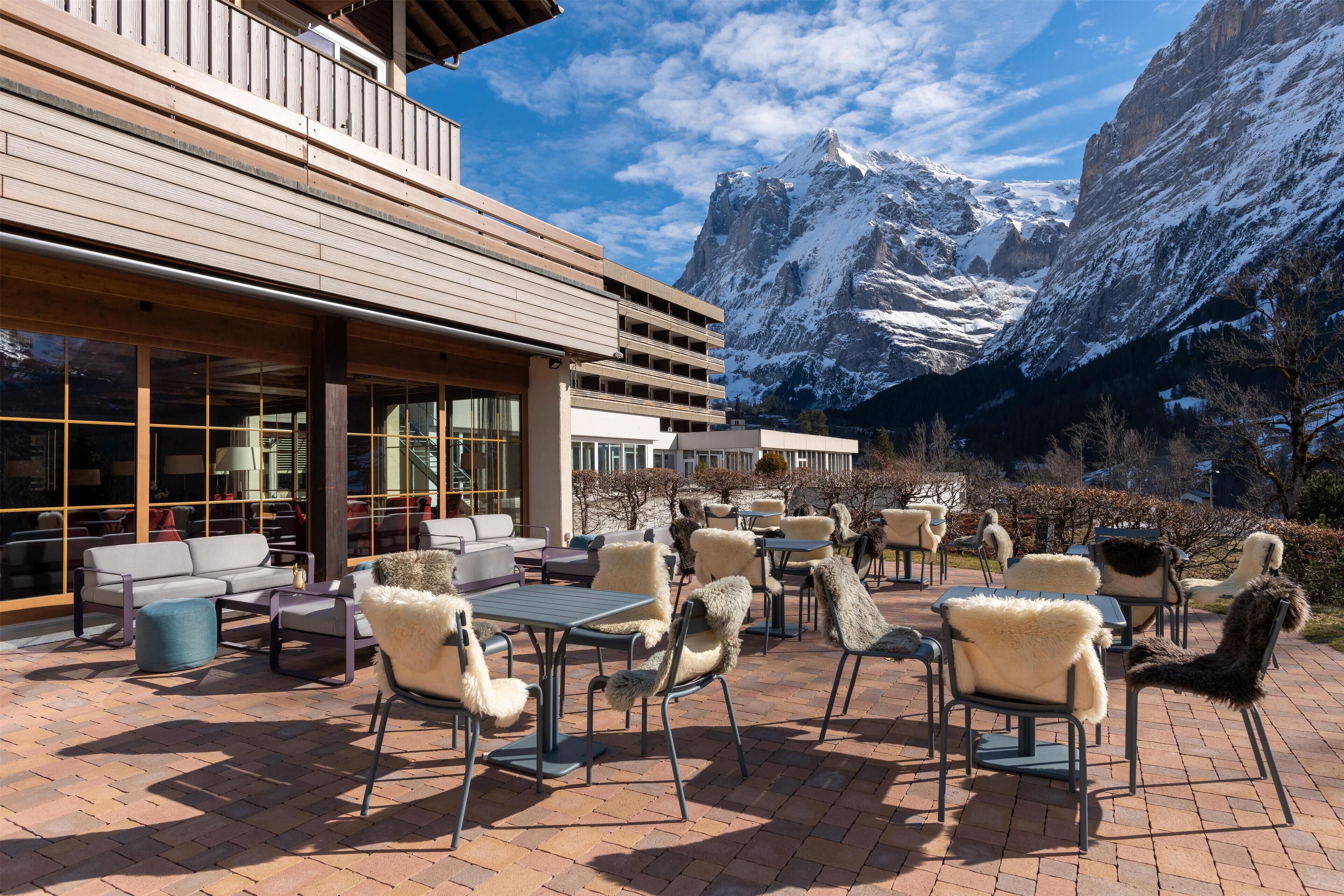 A patio with outdoor seating, a wooden building, and a mountain view.