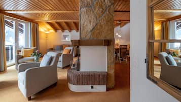 A cozy living room with a stone fireplace, wooden ceiling beams, and comfortable seating.