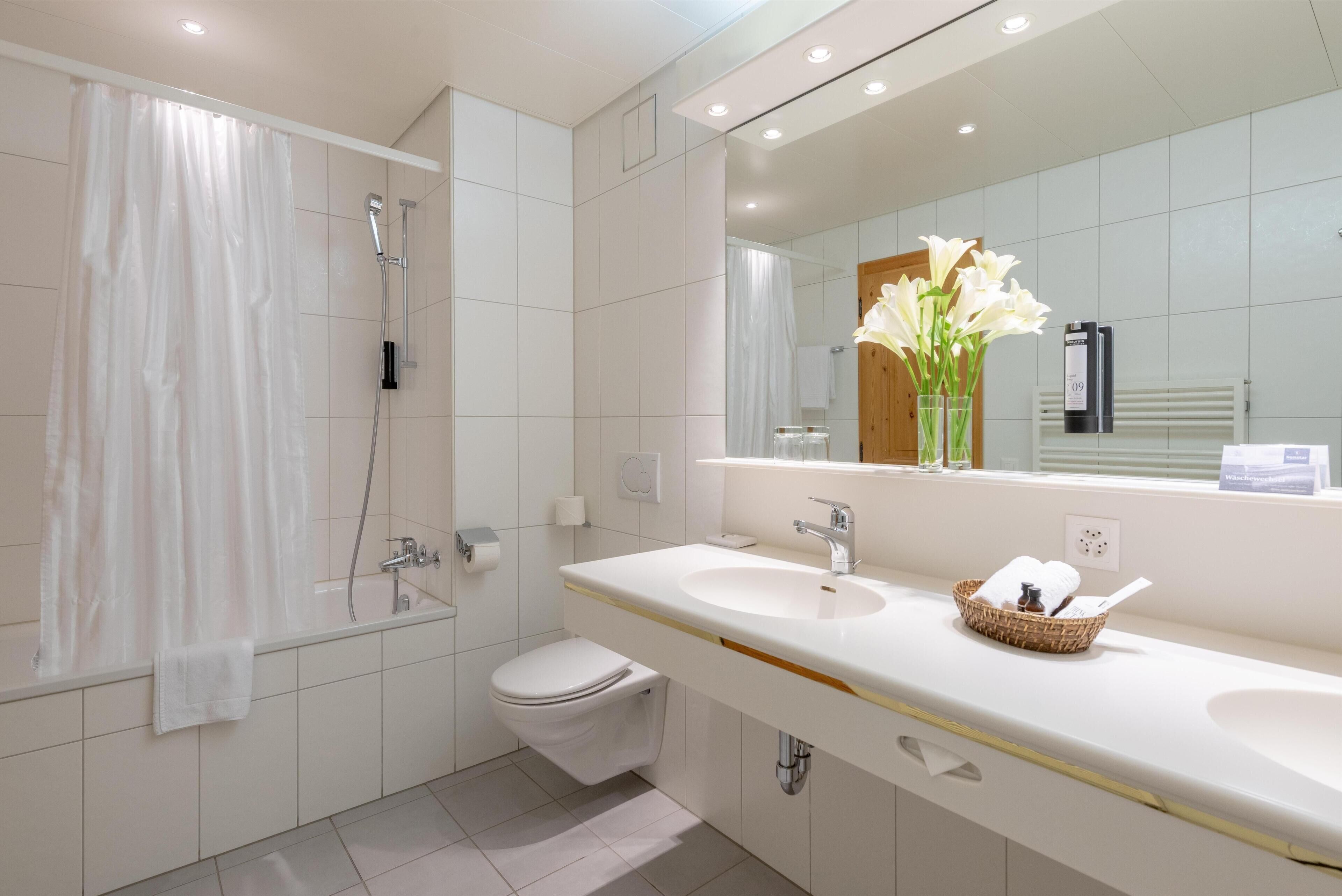 A modern bathroom with a bathtub, toilet, and two sinks.