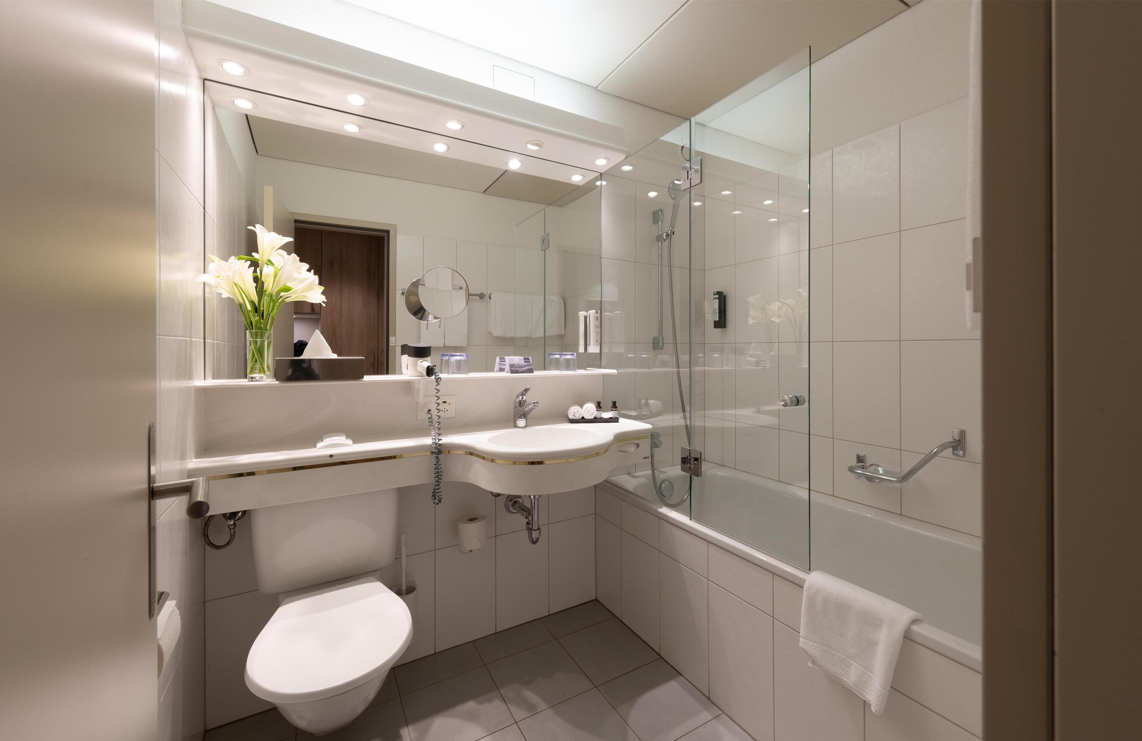 A modern bathroom with a glass-enclosed shower, a white sink, and a toilet.