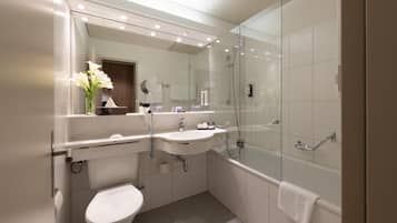 A modern bathroom with a glass-enclosed shower, a white sink, and a toilet.