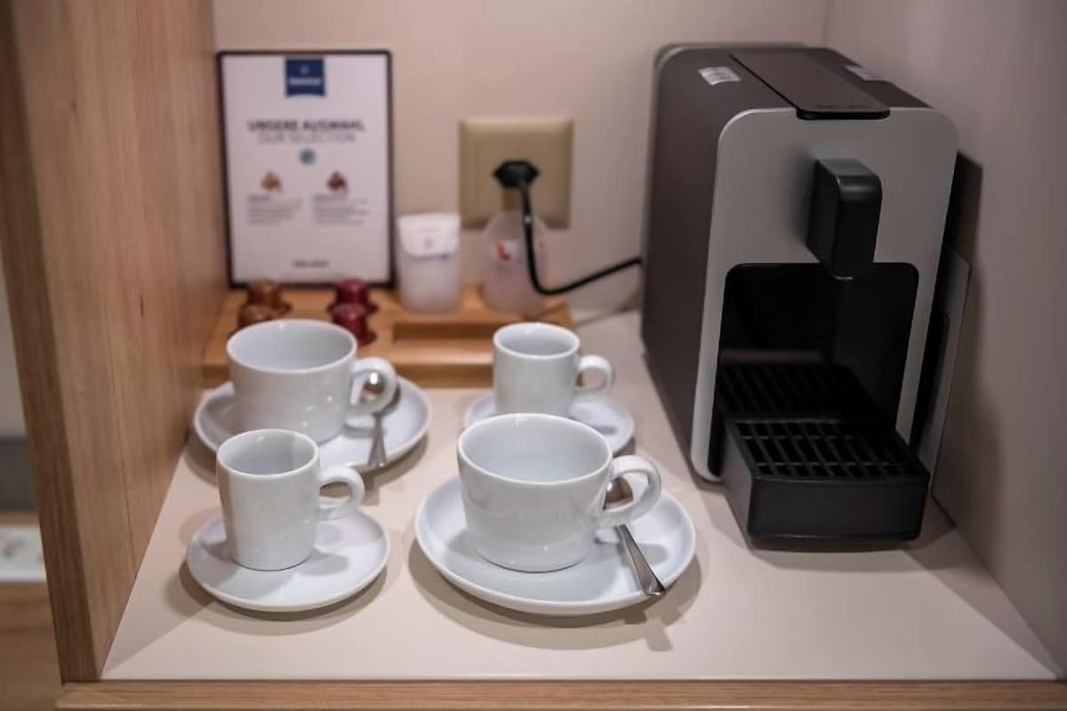En kaffestation med en kaffemaskin, koppar och fat på ett bord.