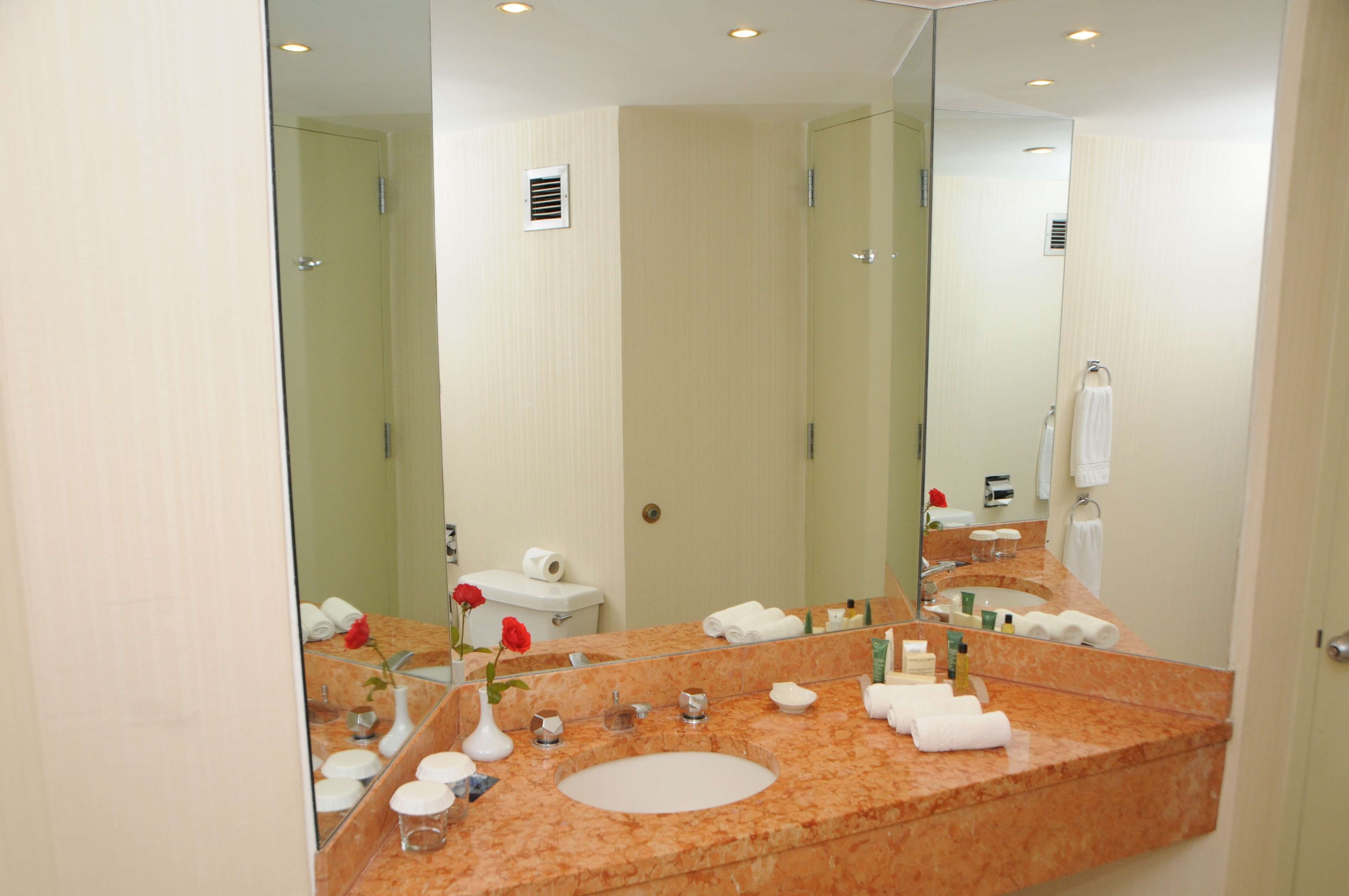 A bathroom with a marble sink, a large mirror, and a toilet.
