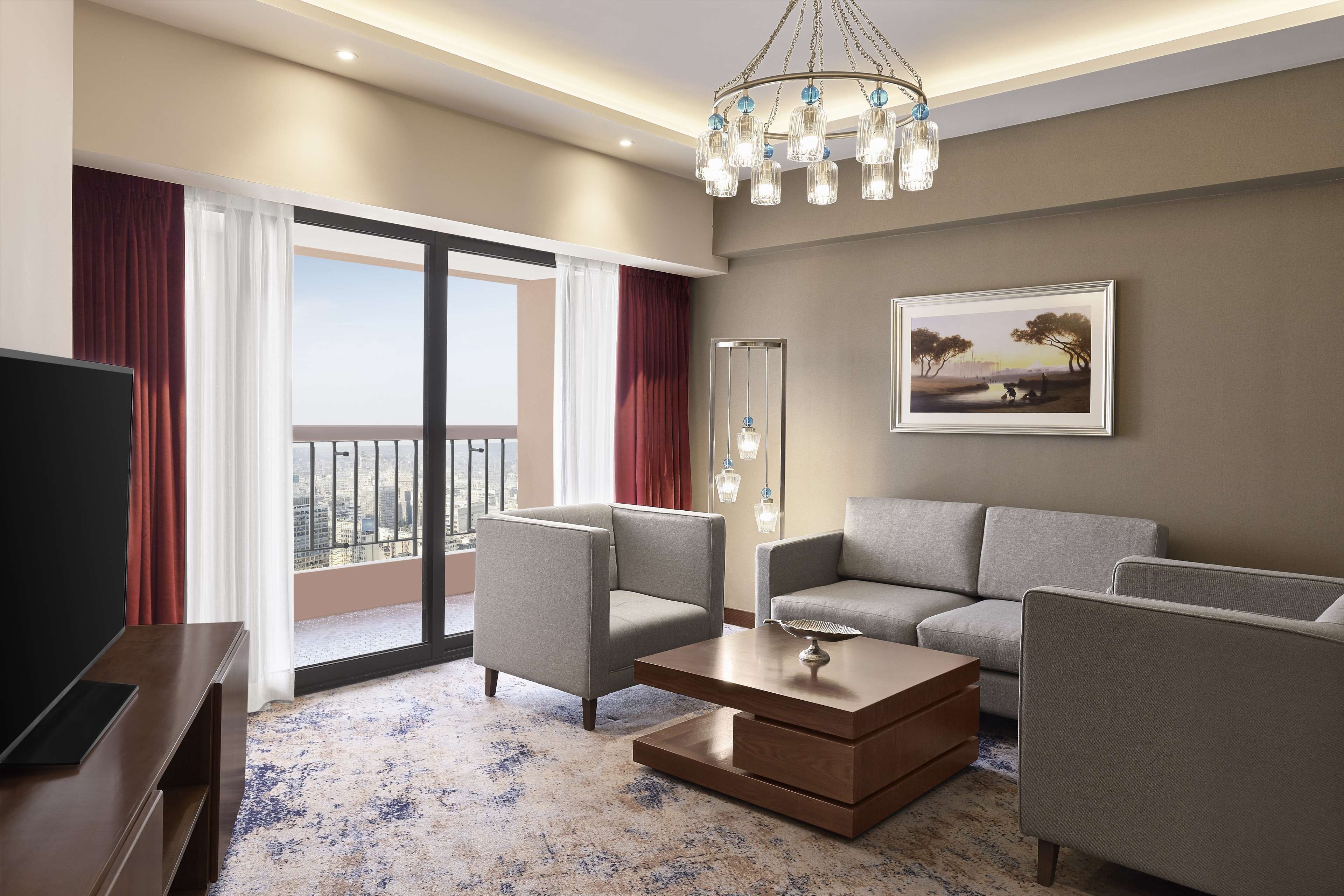 A modern living room with a sofa, armchairs, a coffee table, and a TV.