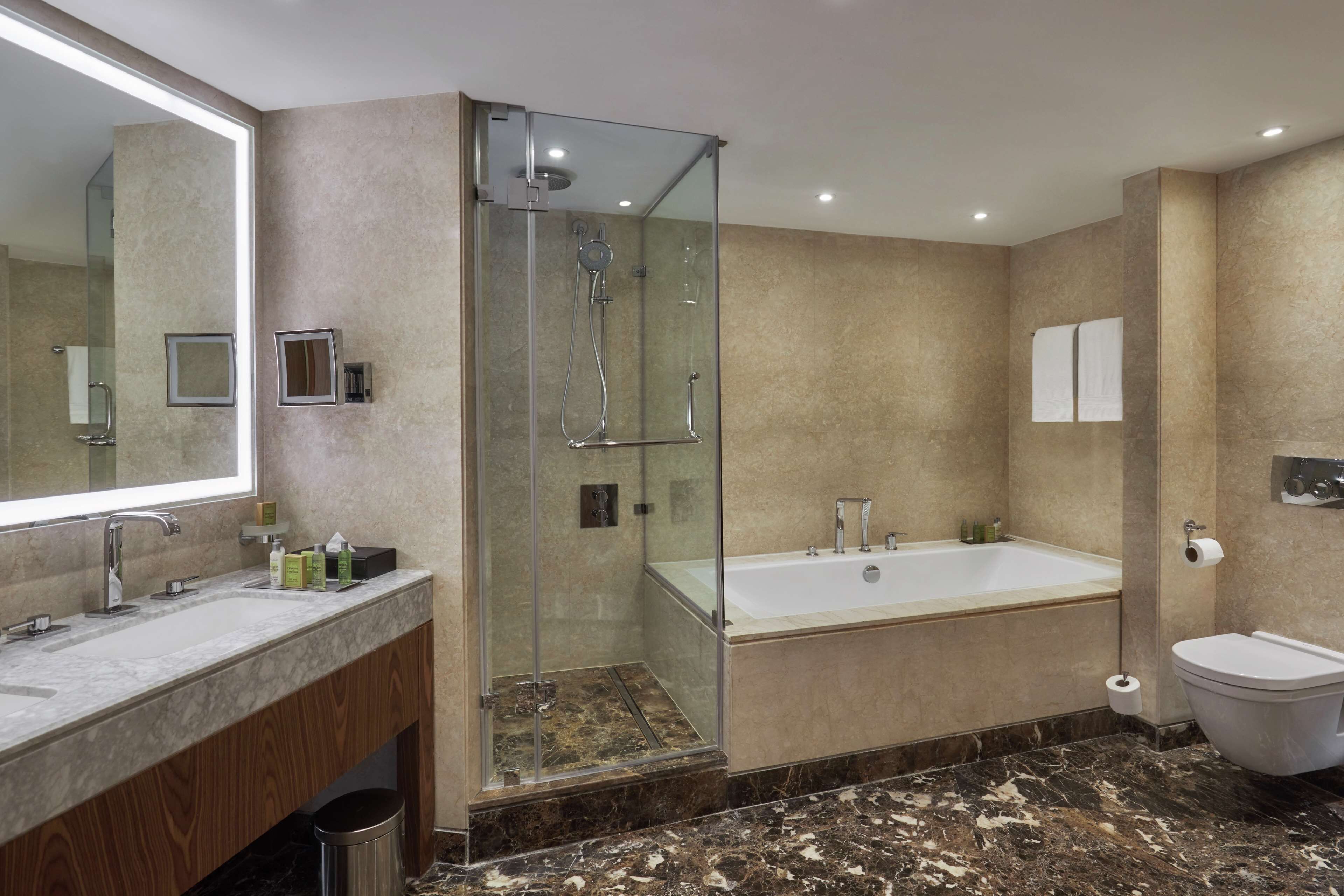 A modern bathroom with a glass-enclosed shower, a large bathtub, and a vanity with a mirror.