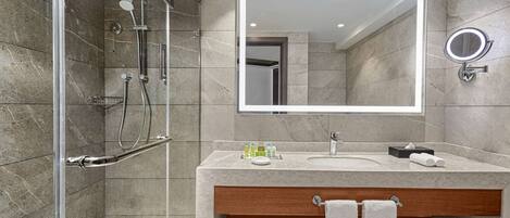 A modern bathroom with a glass-enclosed shower, a large mirror, and a vanity with a sink and towel rack.