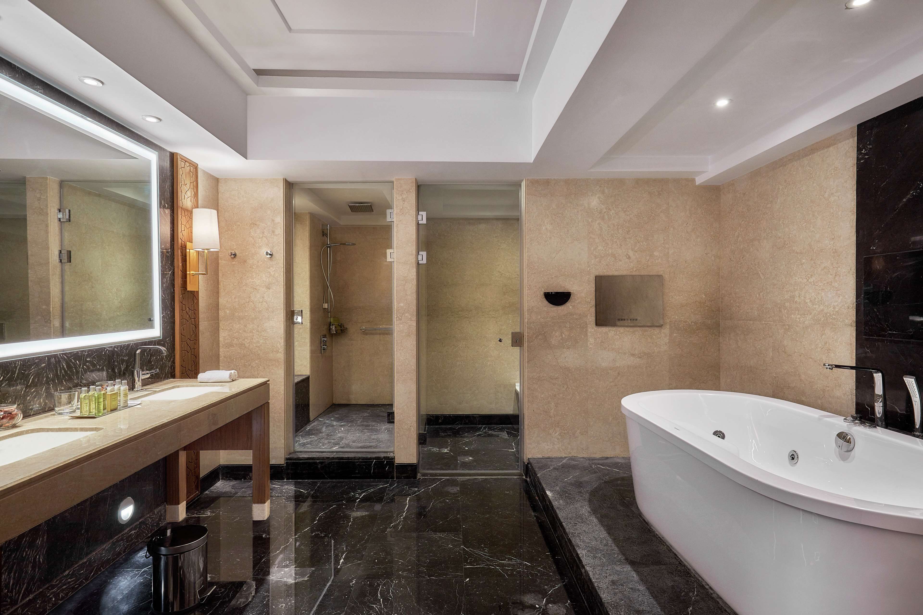 A modern bathroom with a large bathtub, a vanity with a mirror, and a shower area.