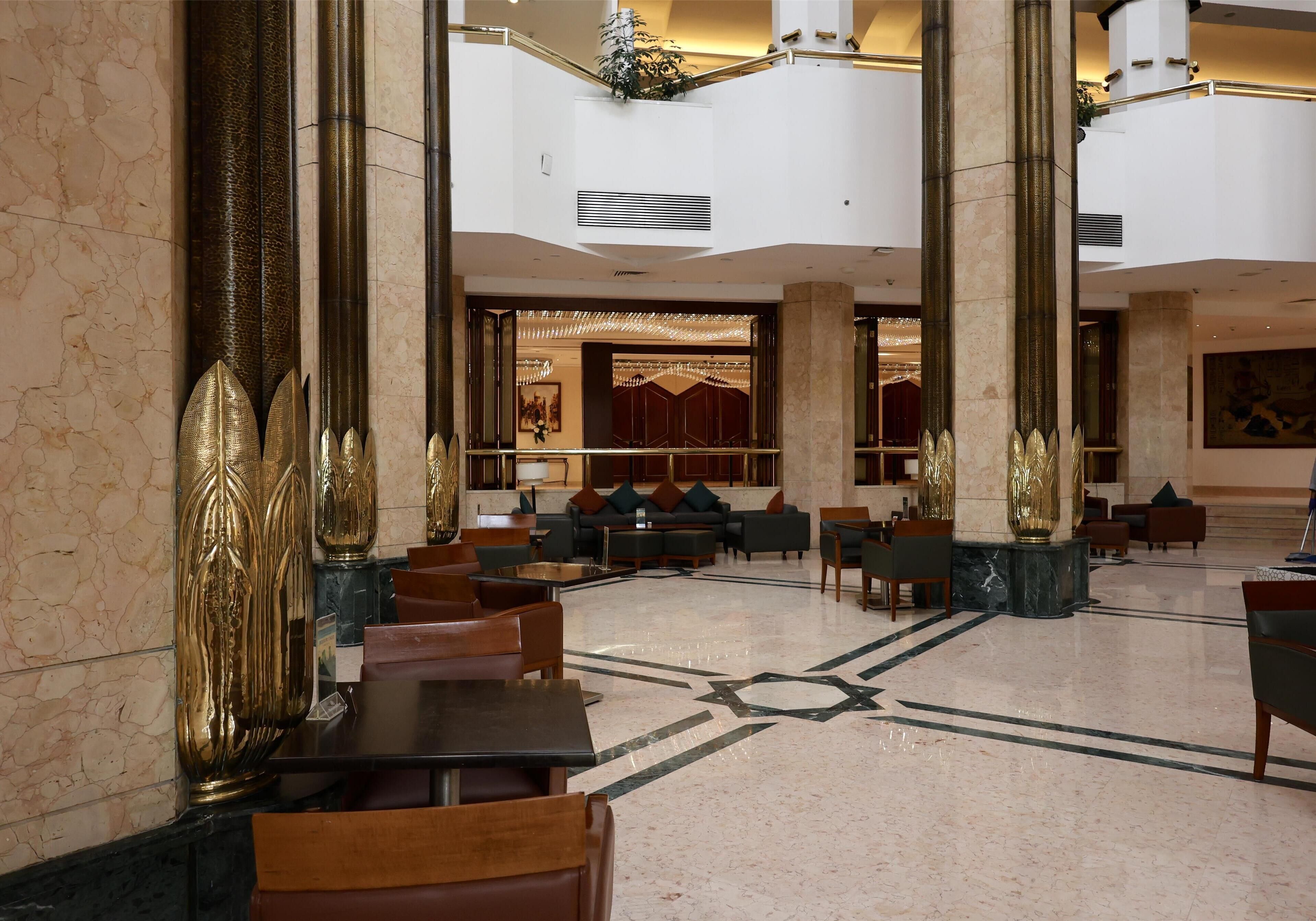 A spacious lobby with marble flooring, high ceilings, and ornate columns.