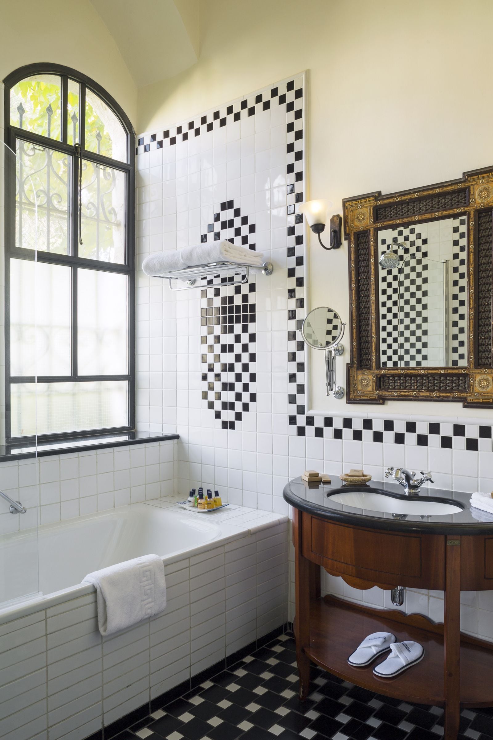 A bathroom with a bathtub, a sink, a mirror, and a window.