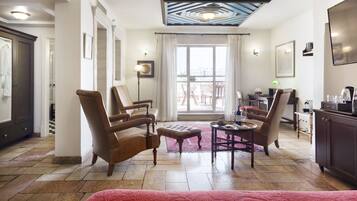 A spacious living room with a large window, a red carpet, and a dining area with chairs and a table.