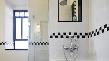 A modern bathroom with a glass-enclosed shower, a bathtub, and a mirror above the sink.