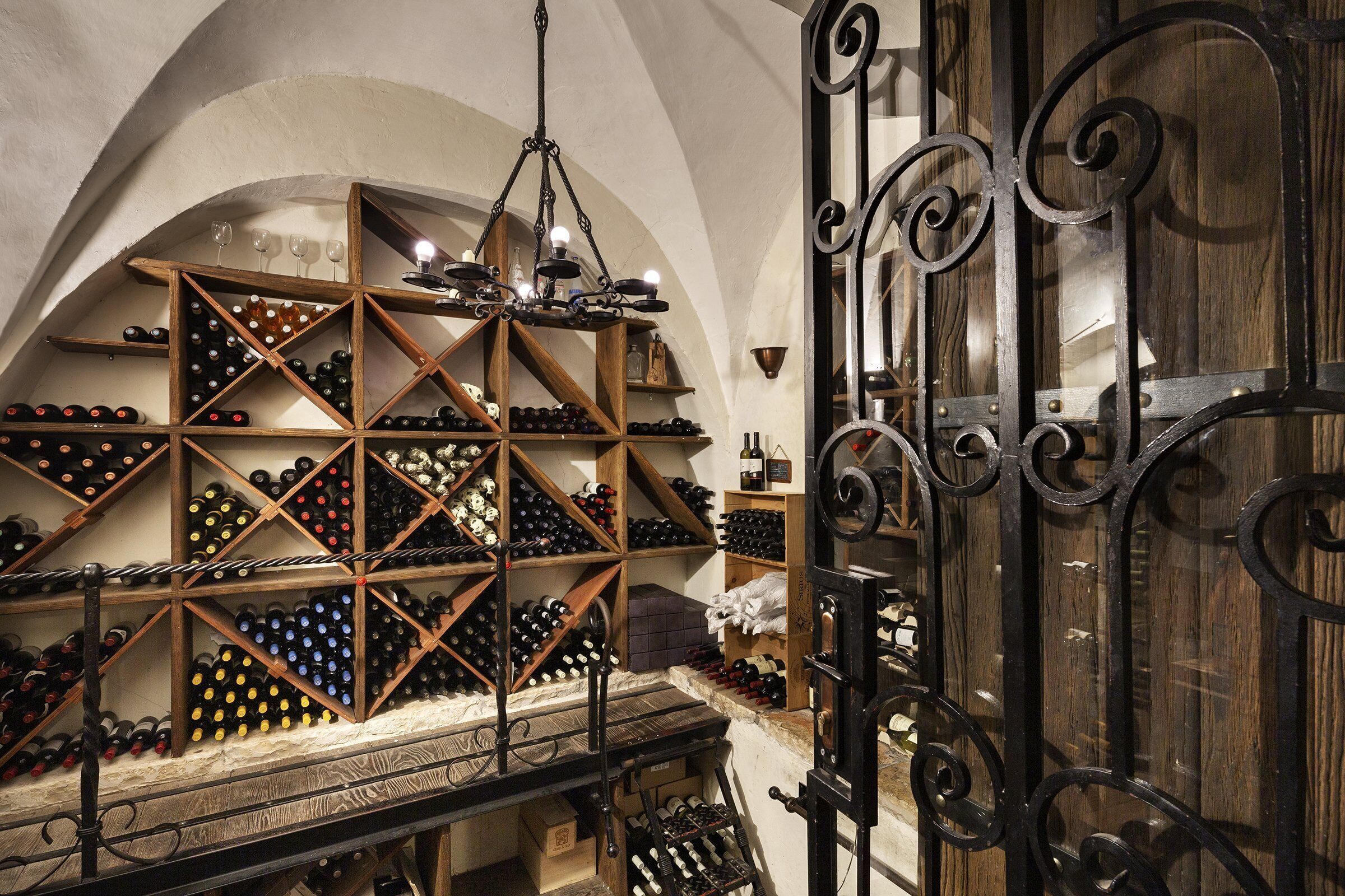 A wine cellar with wooden racks and a chandelier.