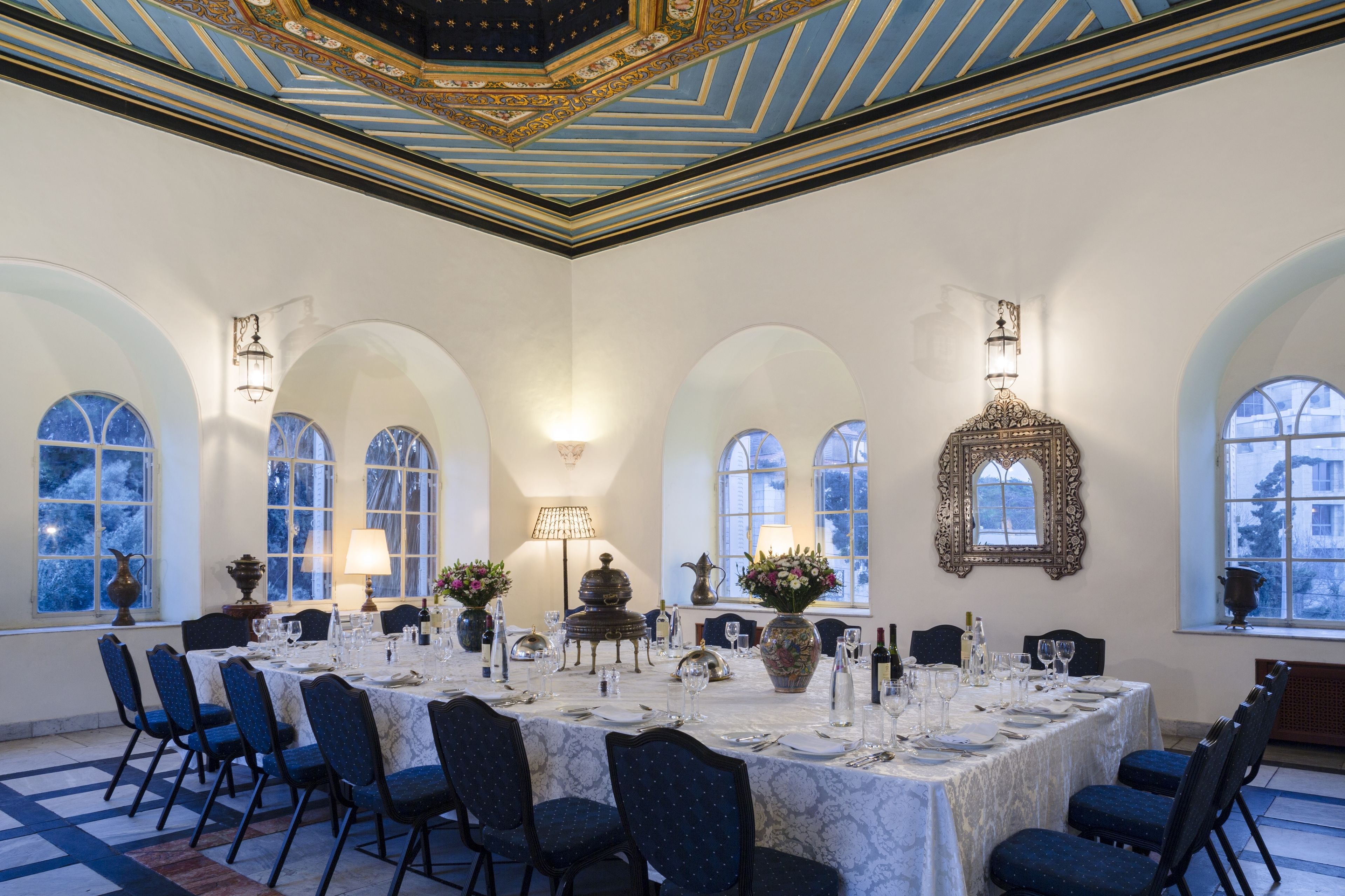 A formal dining room with a long table set for a meal, surrounded by chairs, and decorated with vases and tableware.