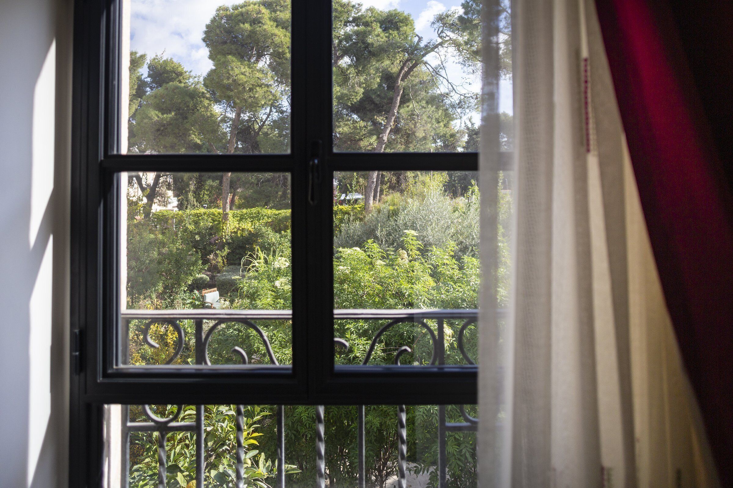 Una ventana con vista a un jardín exuberante y árboles.