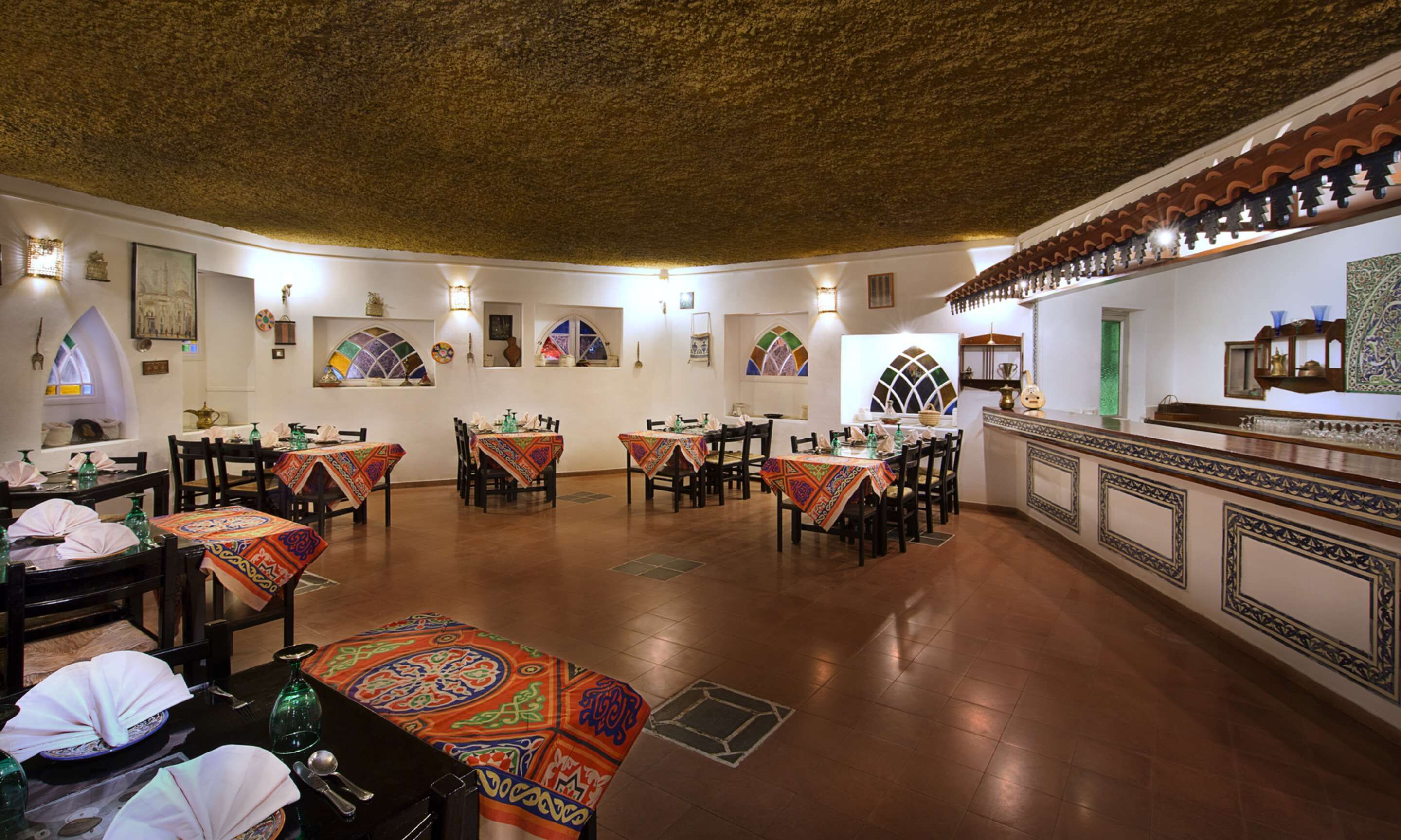 Een eetgedeelte met getoonde tafels, een bar met een toonbank, en decoratieve wandelementen.