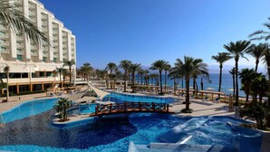 A resort pool with a bridge, palm trees, and a view of the sea. - Steigenberger Hotel & Nelson Village (Taba)