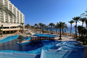 Ein Pool in einem Resort mit einer Brücke, Palmen und Meerblick.