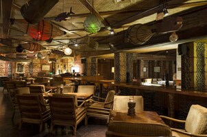Un restaurante con mobiliario de mimbre, faroles colgantes y paredes con diseños.