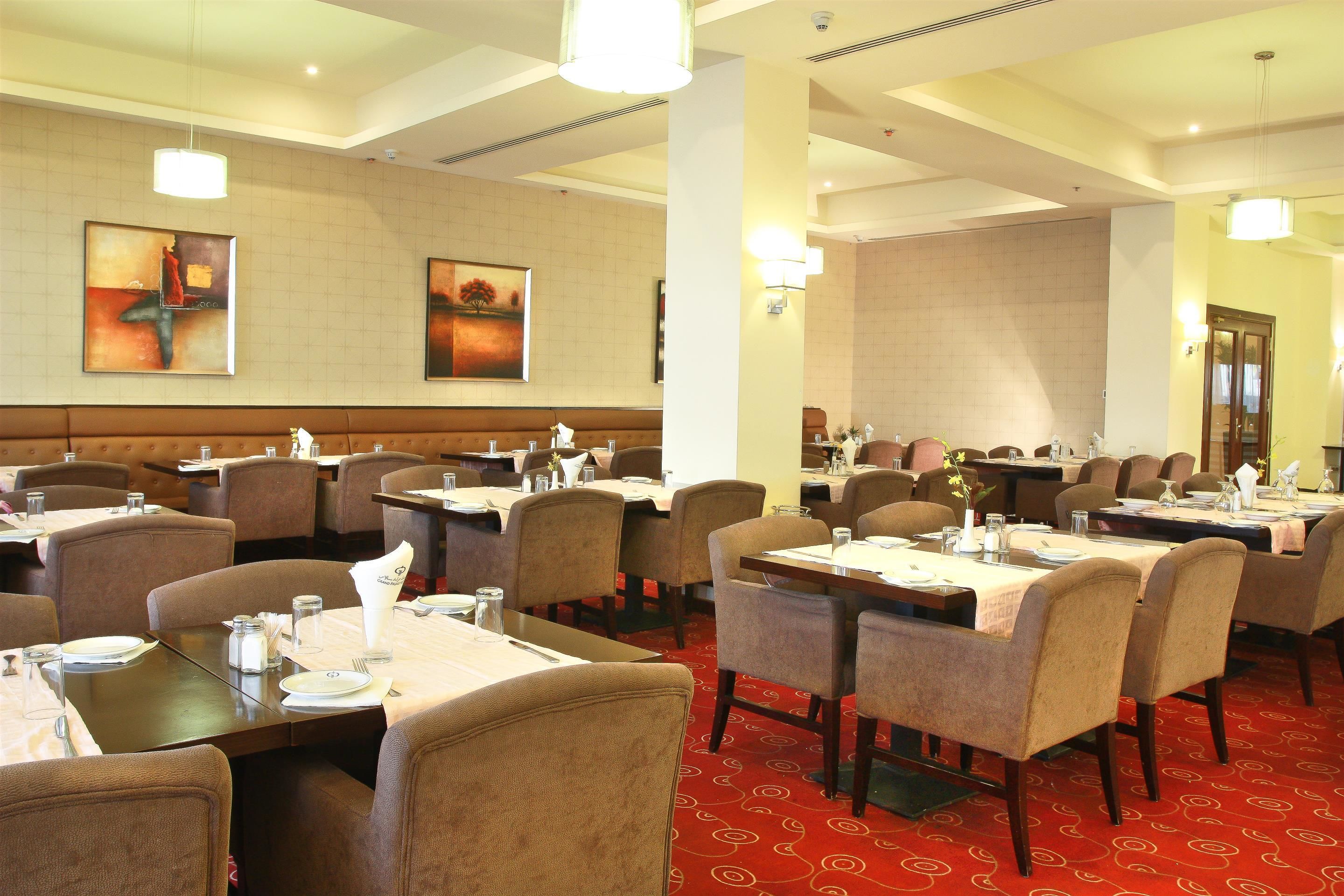 A hotel dining area with multiple tables and chairs, arranged in a spacious layout.