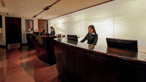 A reception desk with a Samsung laptop, a bulletin board, and a wall with a textured design.
