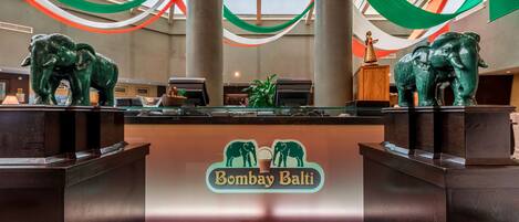 A reception area with a logo for 'Bombay Bali' and two elephant statues on pedestals.