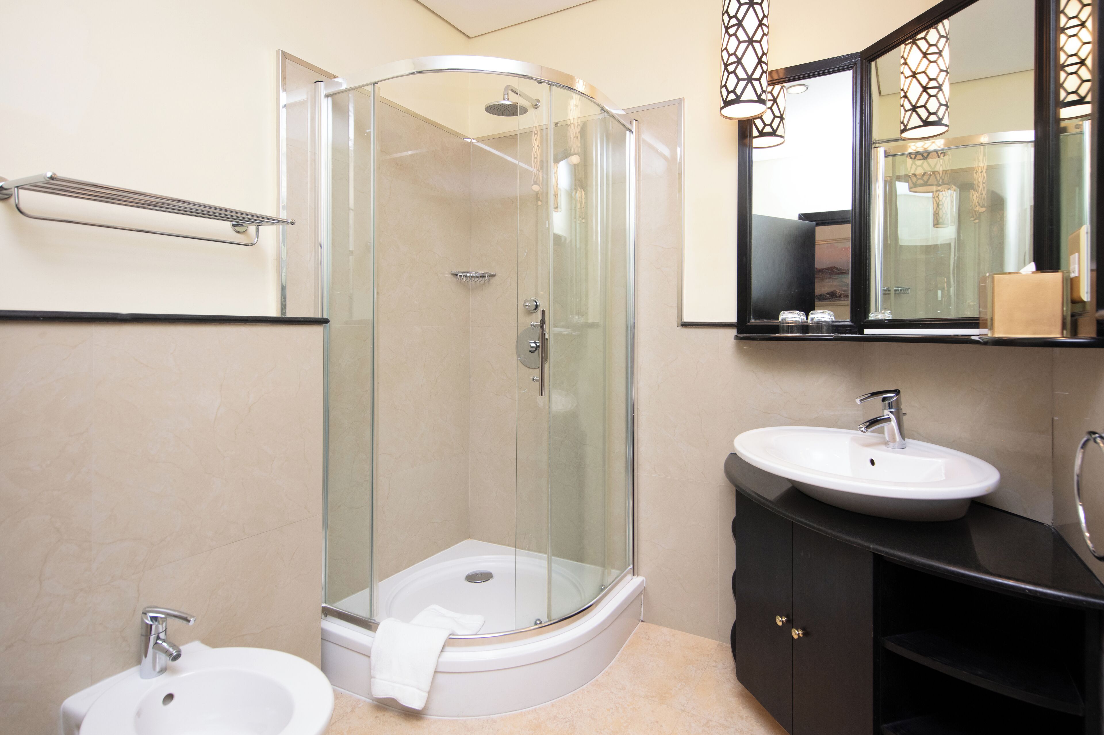 A modern bathroom with a glass-enclosed shower, two sinks, and a vanity with a mirror.
