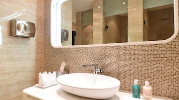 A bathroom with a large mirror, a white sink, and a tiled wall.