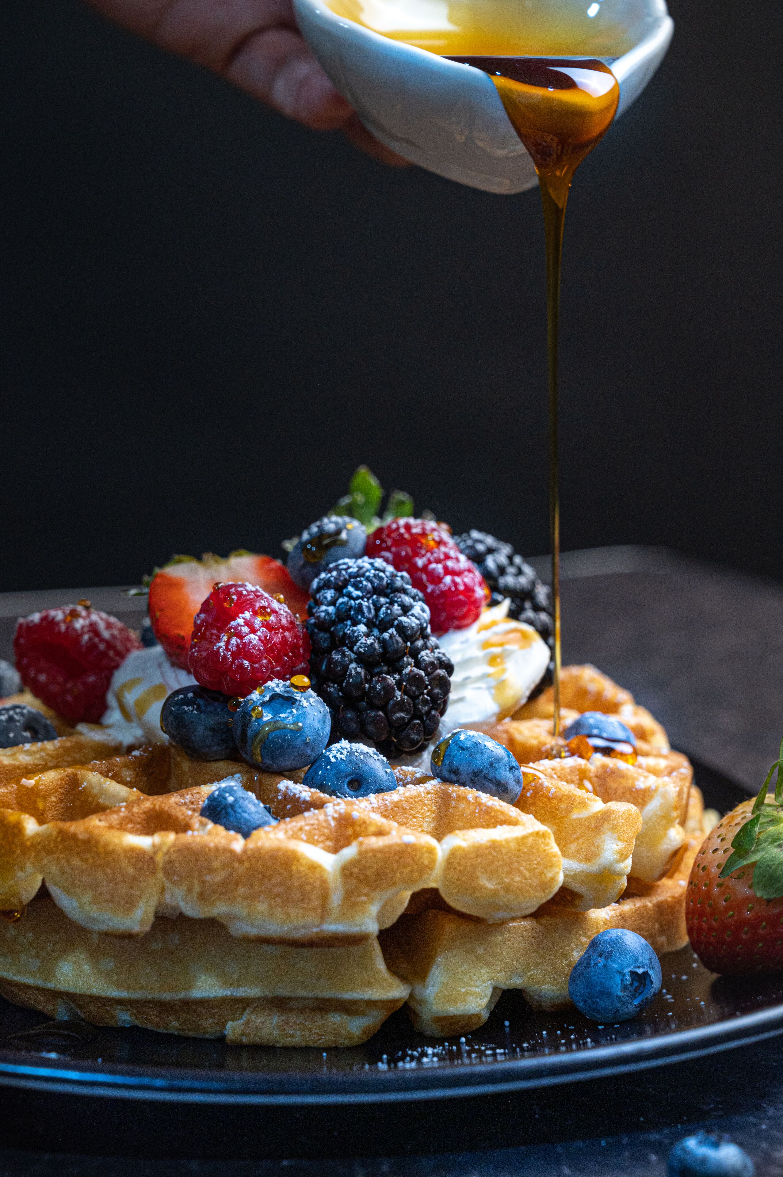 A stack of waffles topped with fresh berries and a drizzle of syrup.