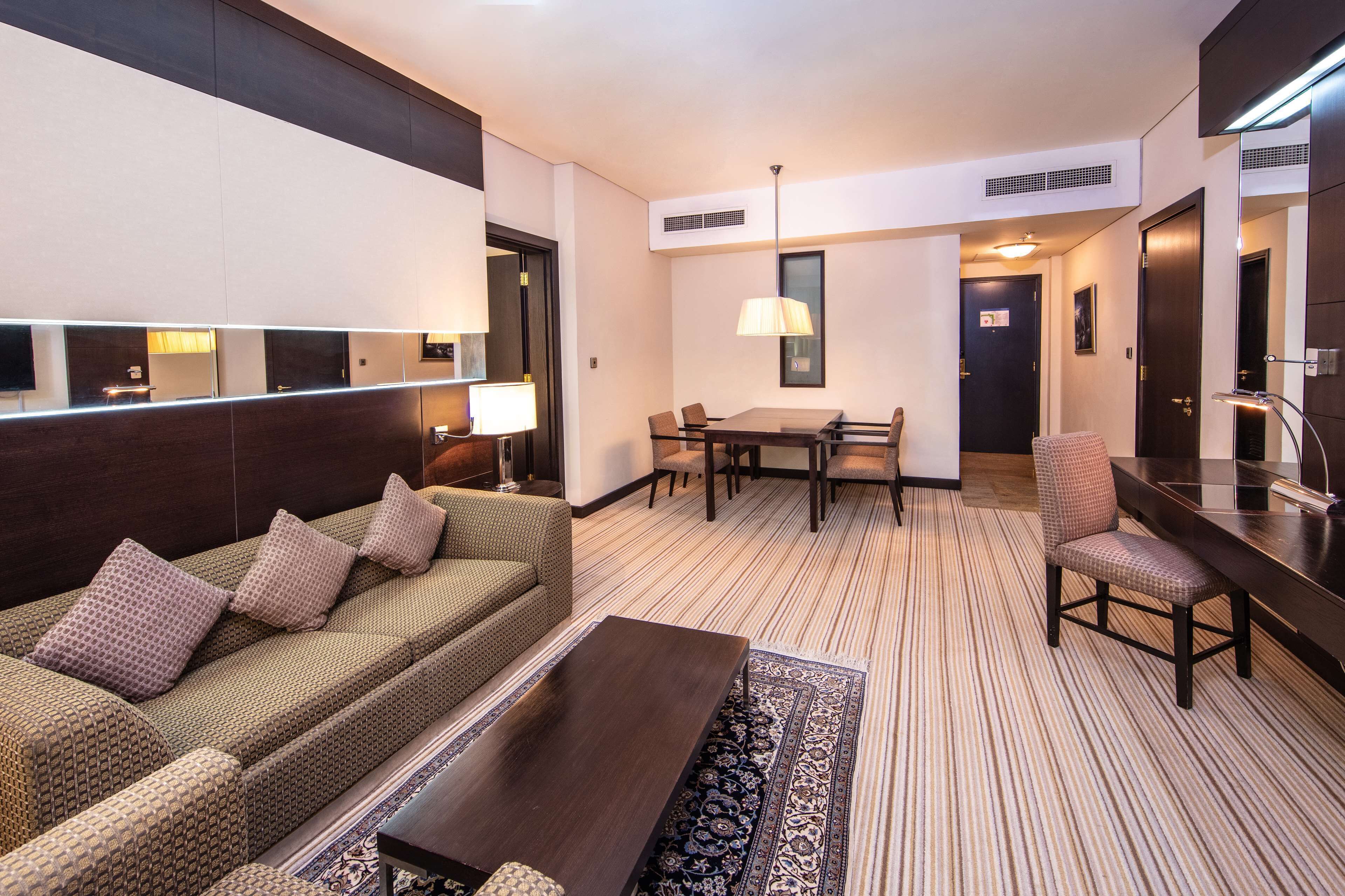 A hotel room with a sofa, a dining table, and a chair.