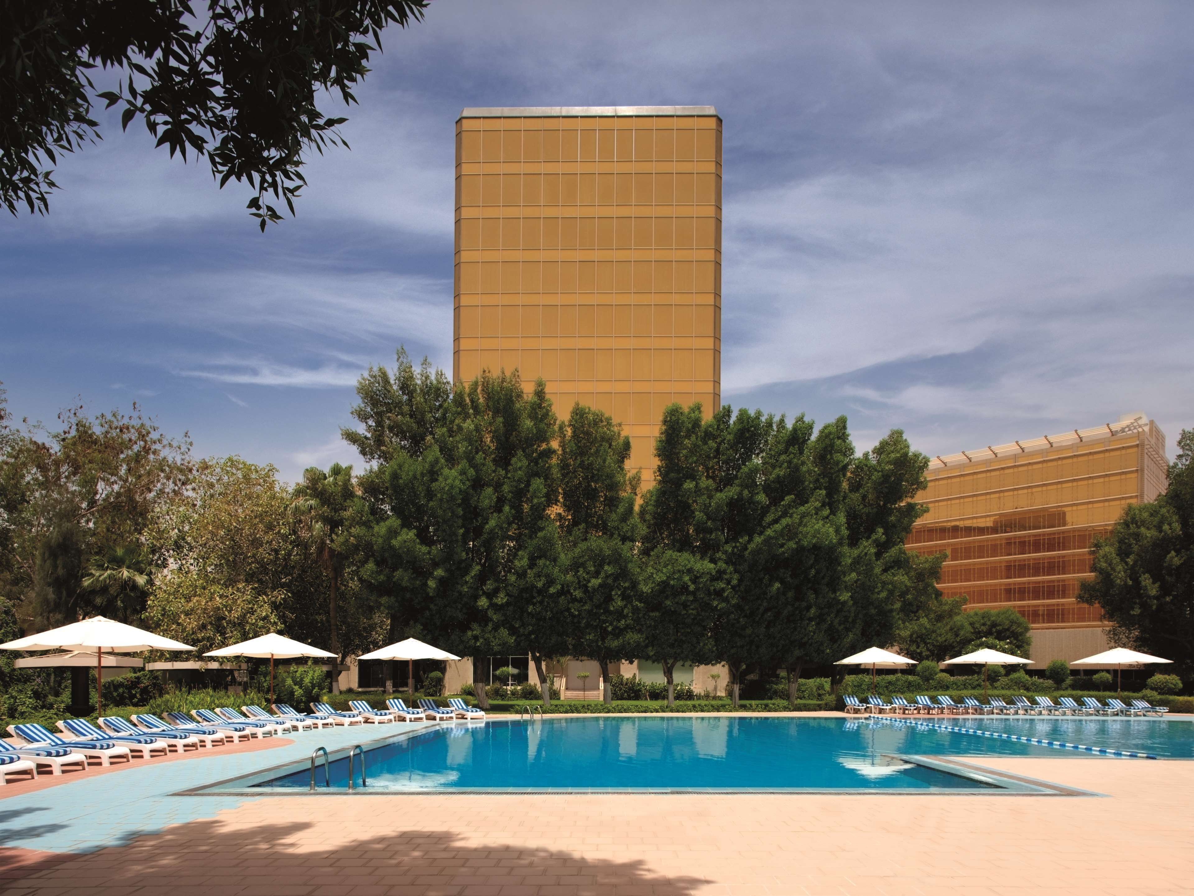 Una piscina al aire libre, sombrillas, sillones reclinables de piscina