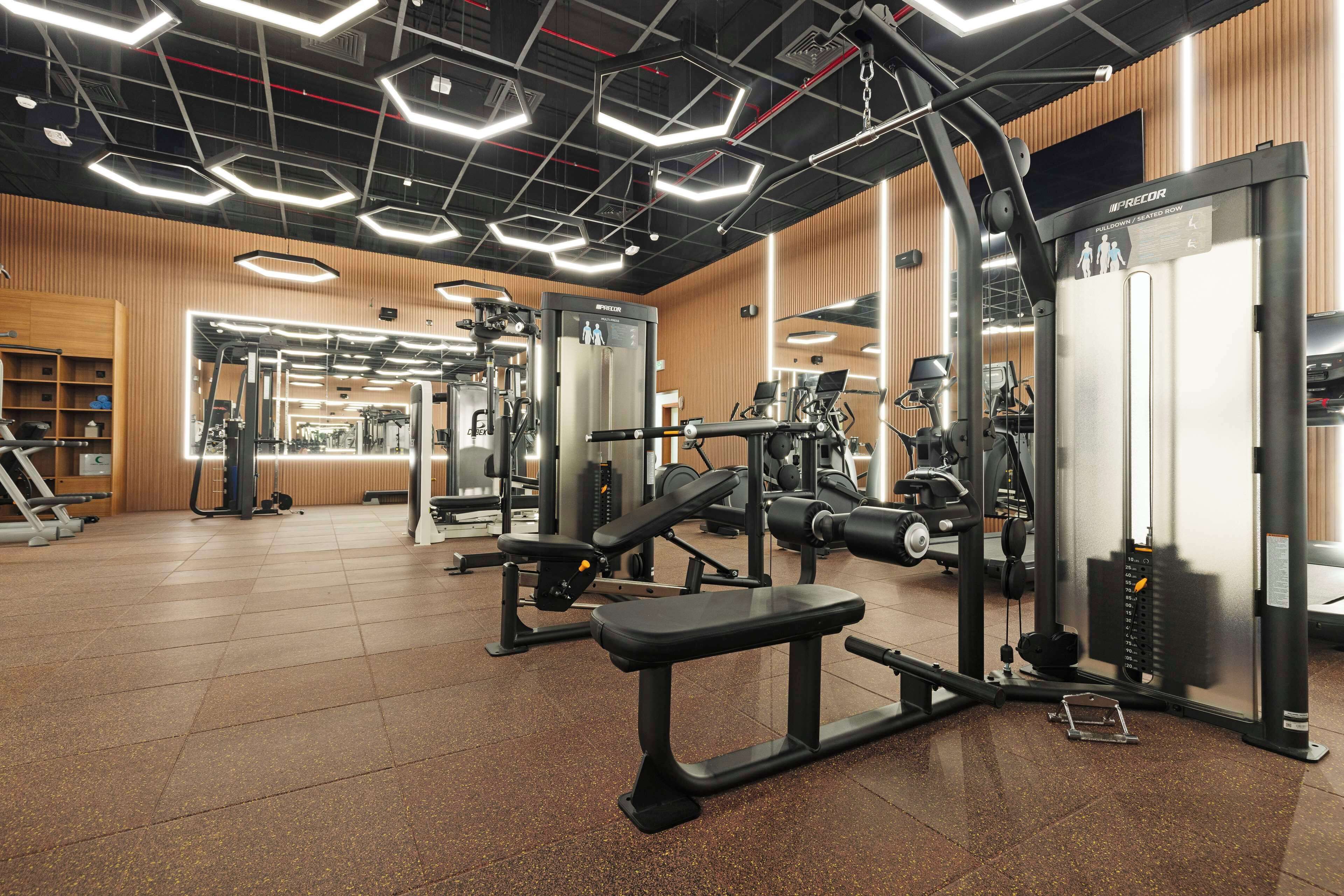 A gym with various exercise equipment, including a bench press, weight machines, and a mirror.