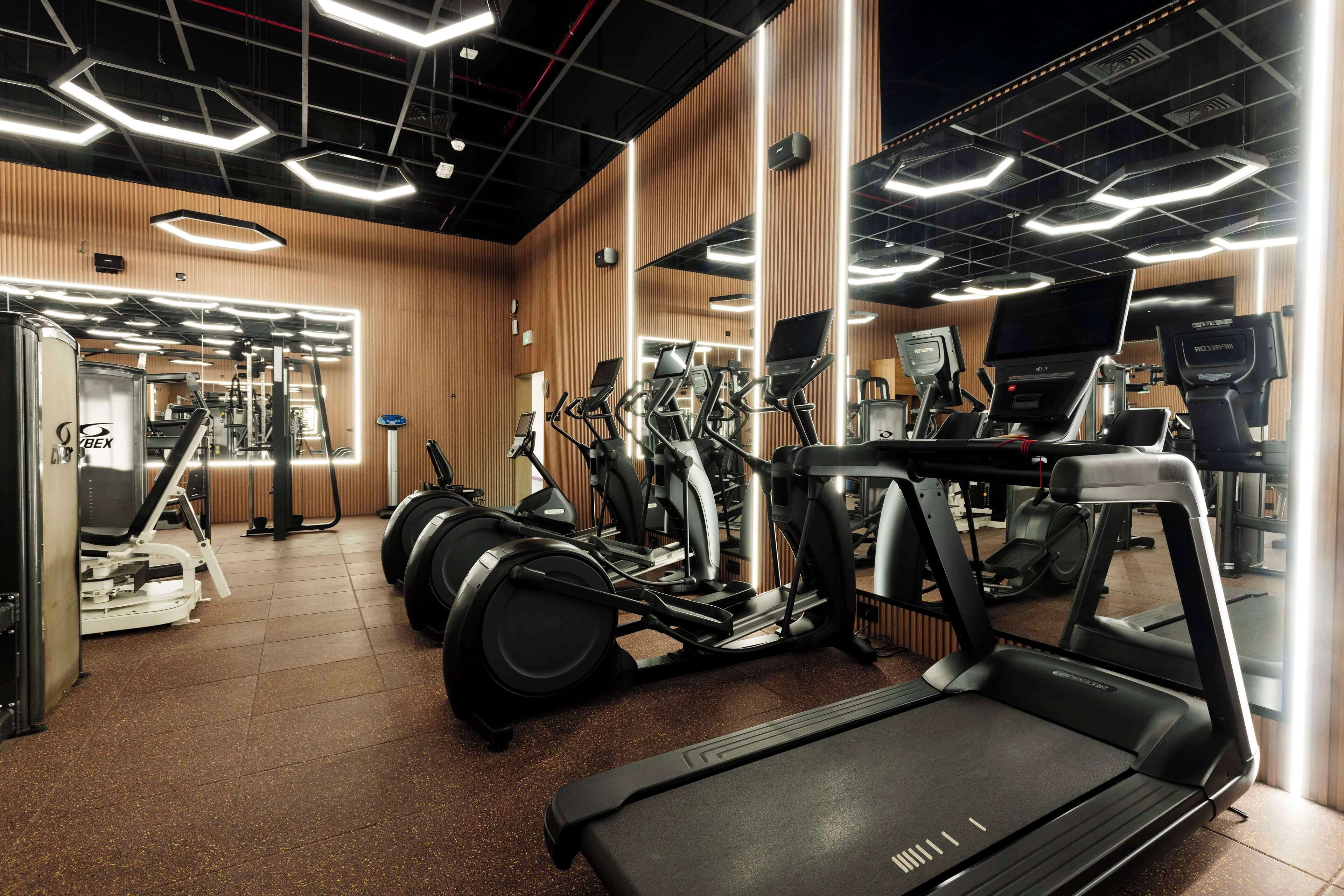 Un gimnasio con cintas de correr, elípticas y equipo de pesas.