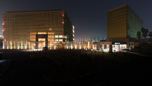 A modern hotel with a large glass facade, multiple floors, and a well-lit entrance area.