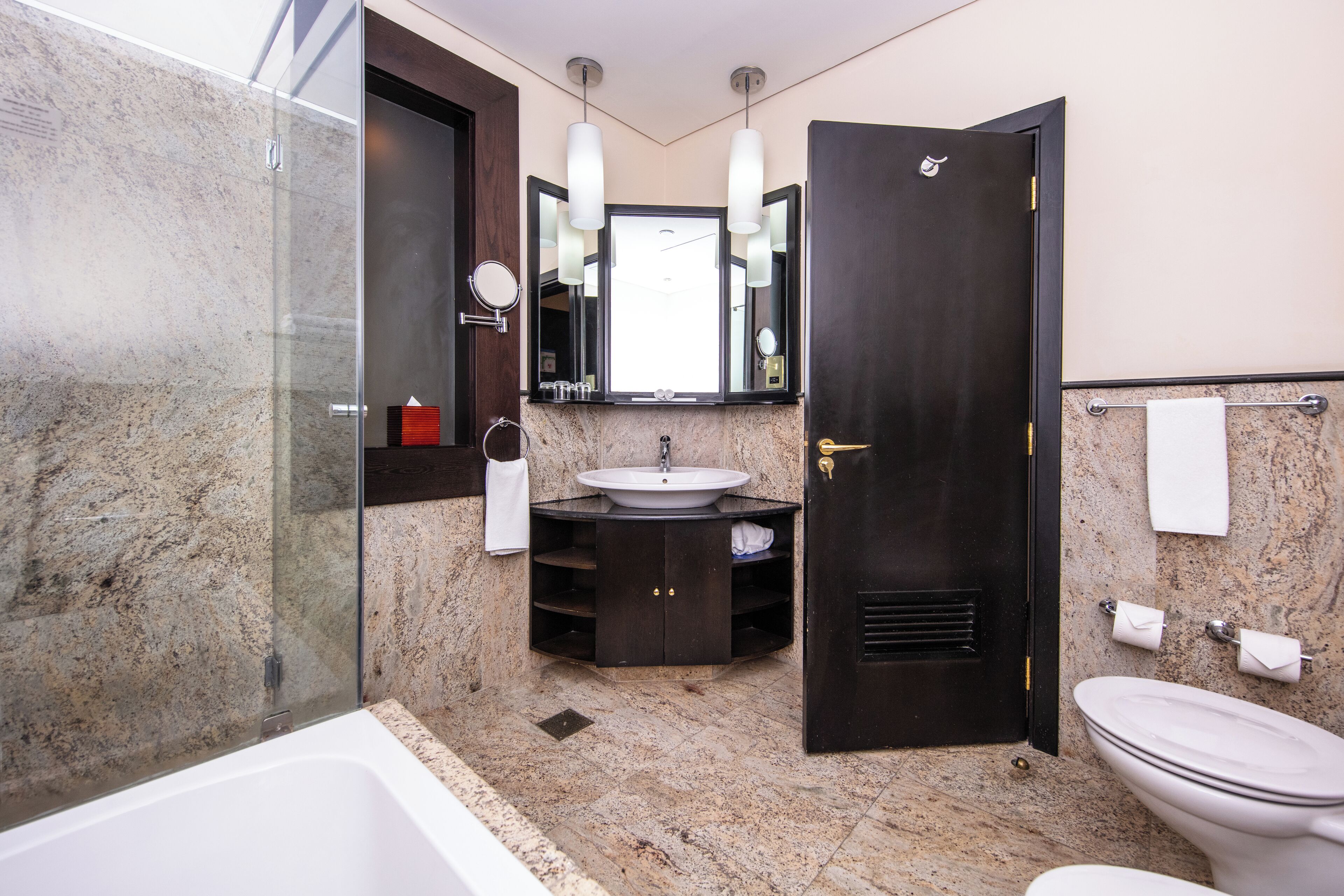 A modern bathroom with a glass shower enclosure, a freestanding bathtub, a vanity with a sink, and a toilet.