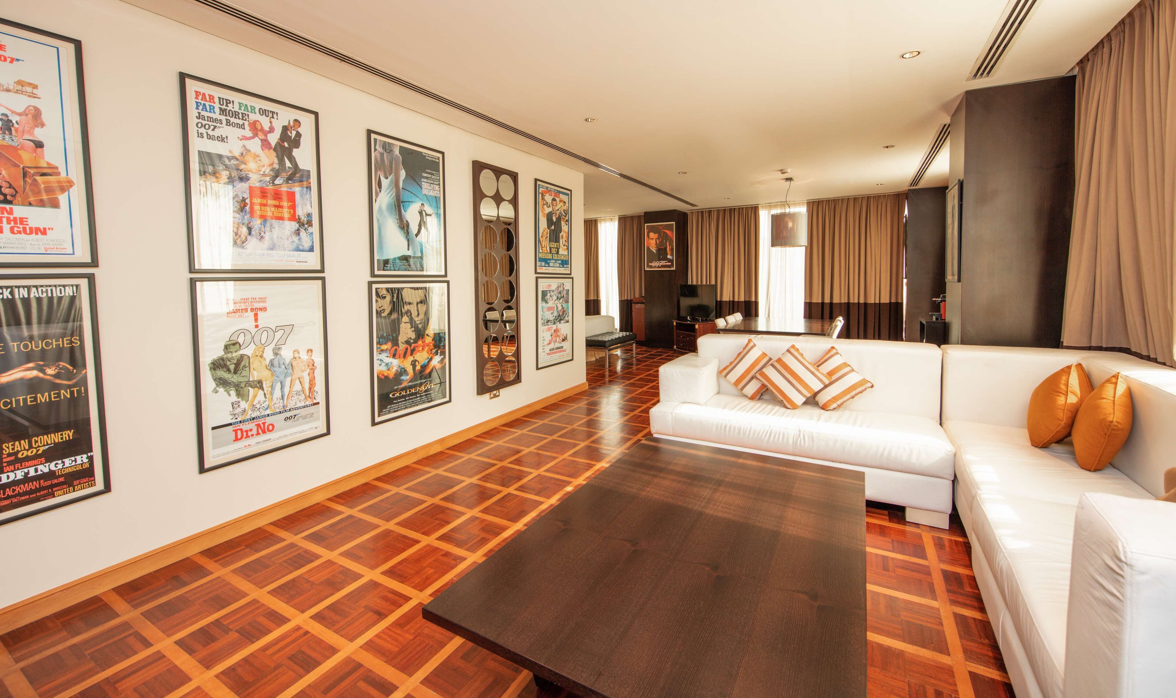 A spacious living room with a white sofa, a coffee table, and a patterned wooden floor.