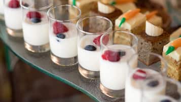 Una presentación de postres con vasitos de yogur coronados con bayas y diferentes pasteles.