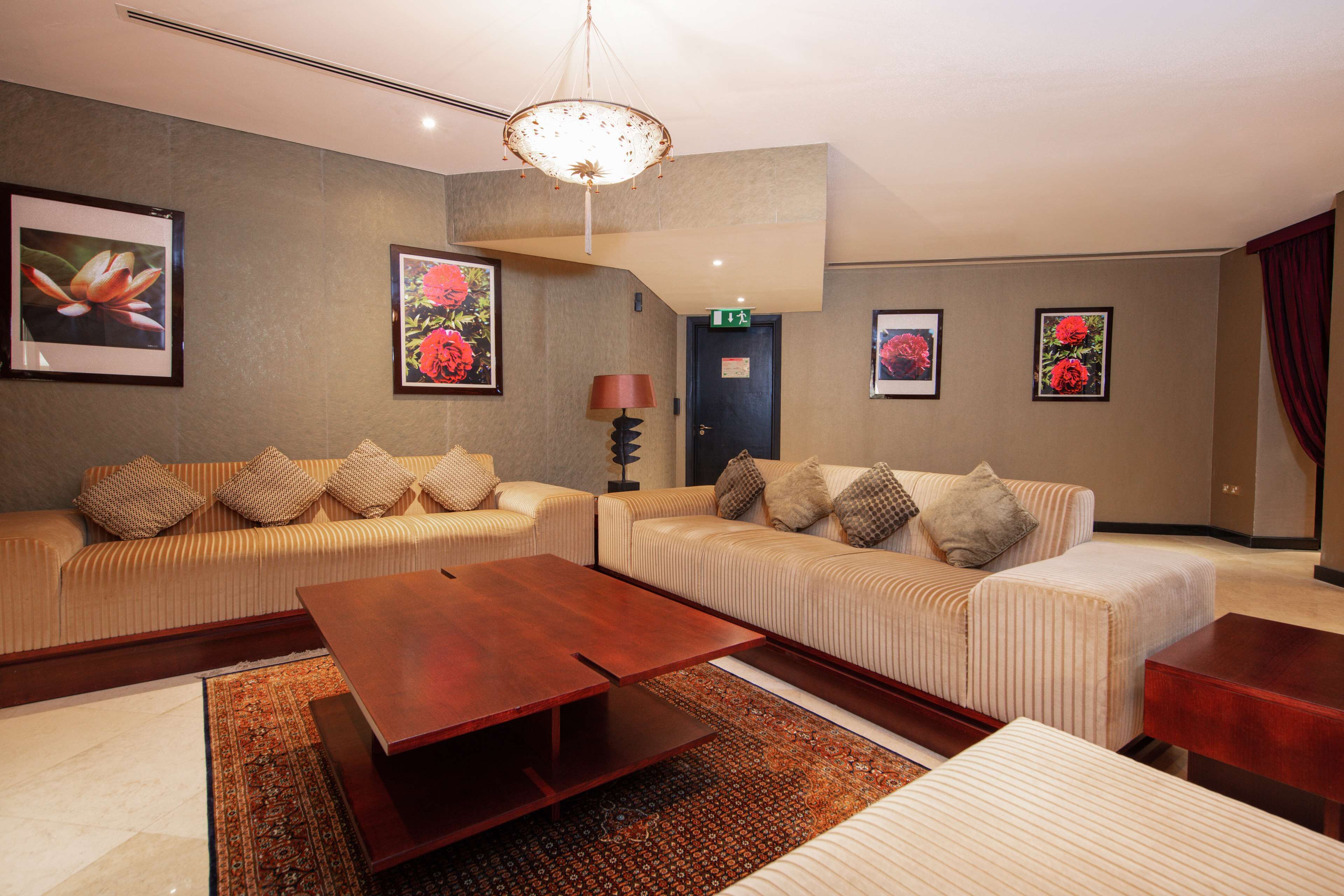 A modern hotel room with two sofas, a wooden coffee table, and a patterned rug.